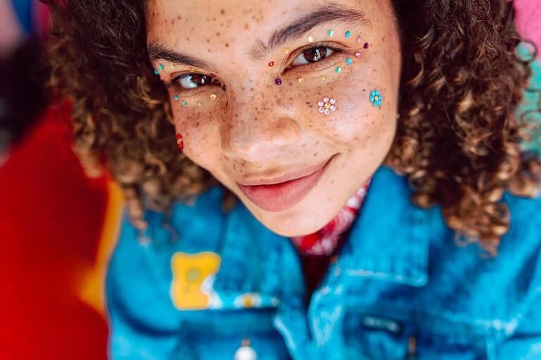 Vibrant portrait featuring a young person with creative face makeup, exuding youthful joy and style.