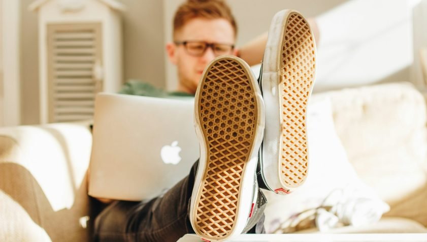 man in black and white sneakers sitting on white couch